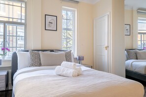 Comfortable accommodations feature a large bed, bedside table, and window with an outside view.