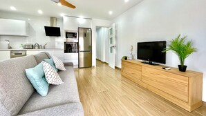 A modern living room with a grey sofa, wooden TV stand, and a ceiling fan.
