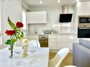 A modern kitchen with white cabinets, a dishwasher, a microwave, and a TV mounted above the counter. - Chaves House by Gloove (santa pola)