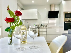 Ein Esstisch mit einer Weinflasche, zwei Weingläsern und einer Rosenvase.