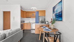 Une cuisine compacte dotée d’appareils électroménagers modernes, un coin repas avec une table ronde et des chaises, et un salon avec un canapé.