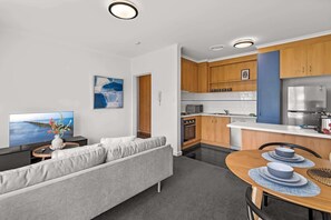 Una cocina moderna con armarios de madera, microondas integrado y refrigerador de acero inoxidable.