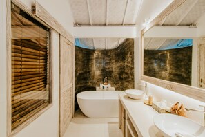 A modern bathroom with a freestanding bathtub, a large mirror, and a vanity with a sink.