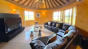 Un salón amplio con un sofá modular grande, un televisor de pantalla plana y un ventilador de techo.