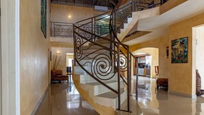 Un interior espacioso con una escalera curva, suelos pulidos y un comedor.