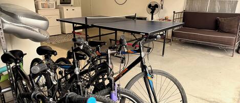 Una habitación con bicicletas, mesa de ping pong, sofá y lavadora.
