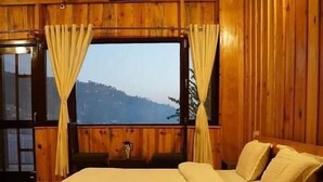 Una habitación de madera con cama, cortinas y ventana con vistas.