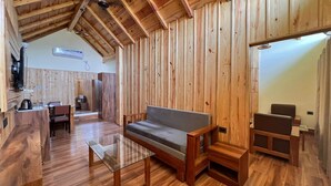 Un interior de madera con un sofá, una mesa de centro de vidrio y un comedor.