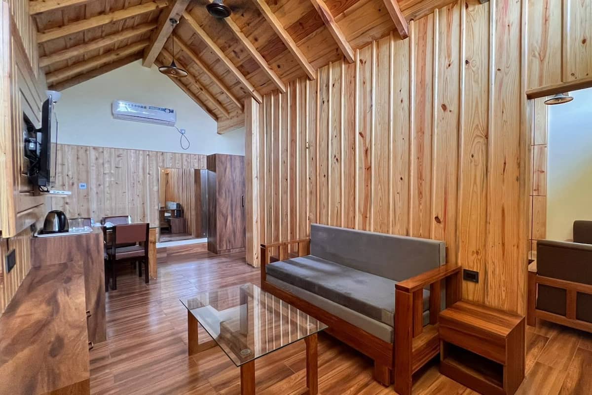 A wooden interior with a sofa, a glass coffee table, and a dining area.
