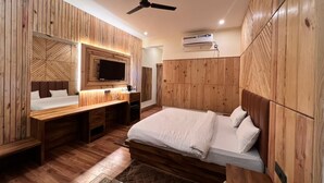 Un dormitorio con cama, escritorio y televisor.