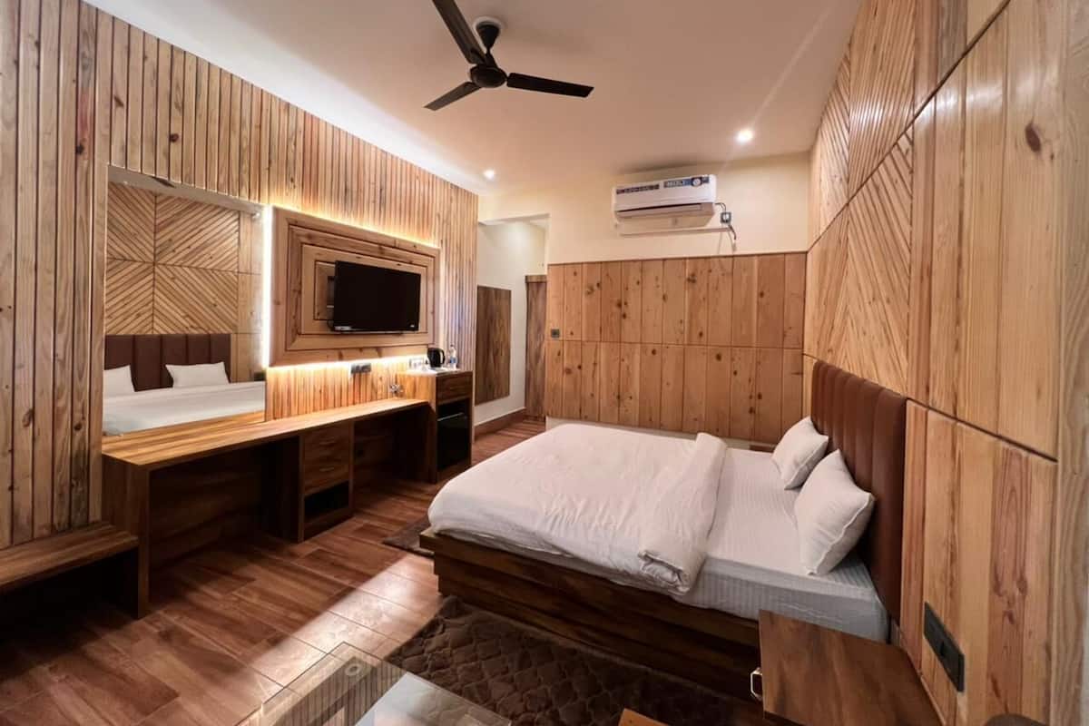 A bedroom with a bed, a desk, and a television.