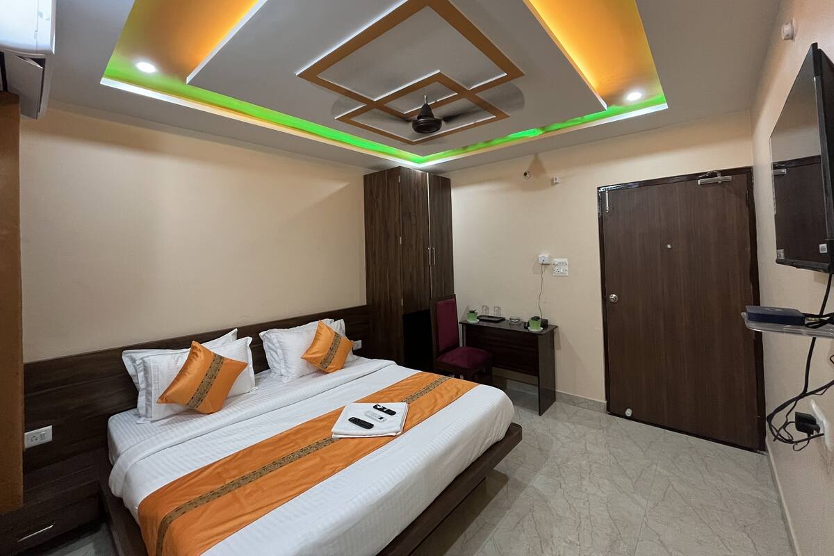 A hotel room with a bed, a desk, a wardrobe, and a TV.