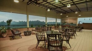 An outdoor dining area with tables and chairs, large windows, and potted plants. - Onyx Hotel & Villa (Bintan)