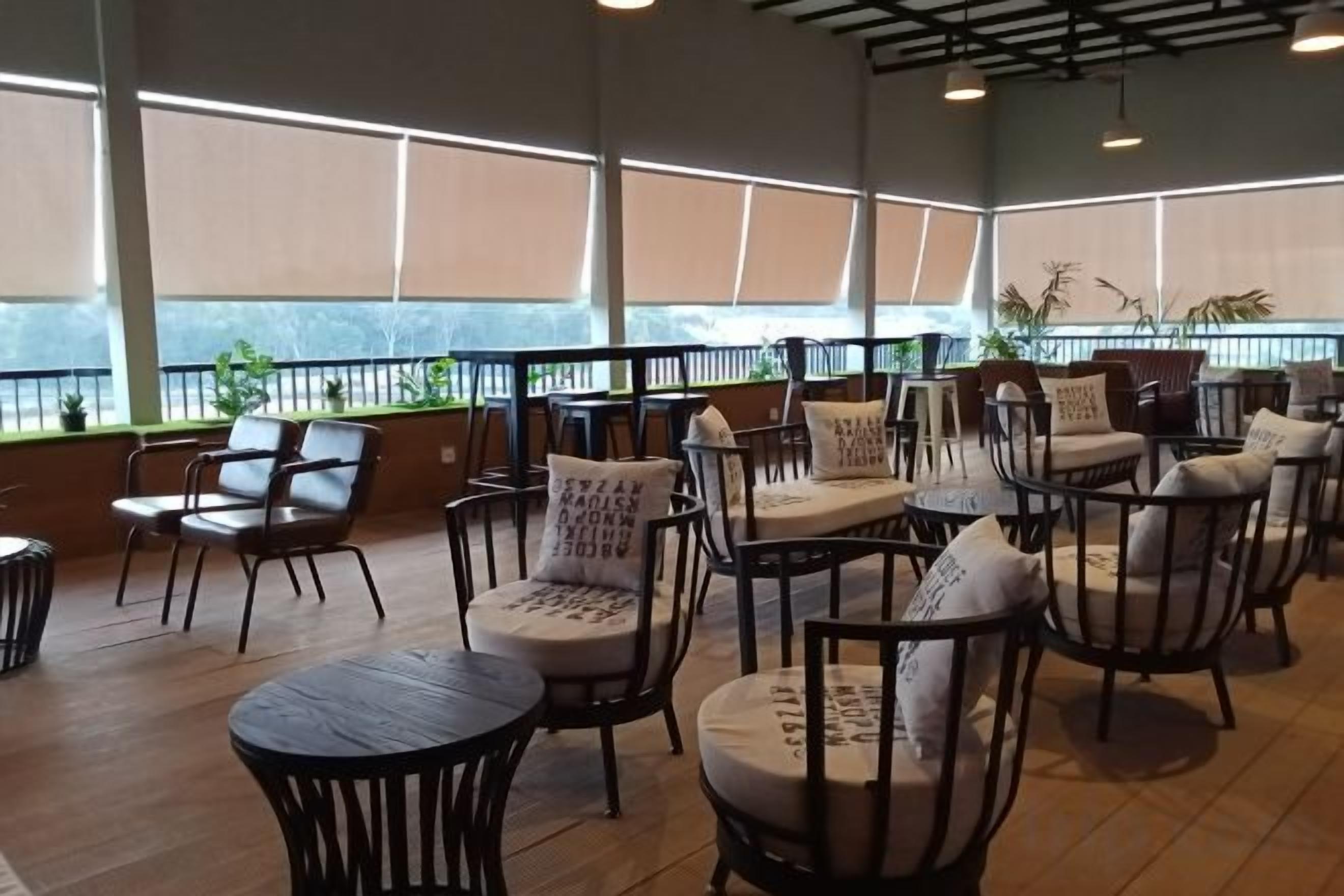 A spacious indoor seating area with multiple chairs and tables, large windows, and a view of the outdoors.