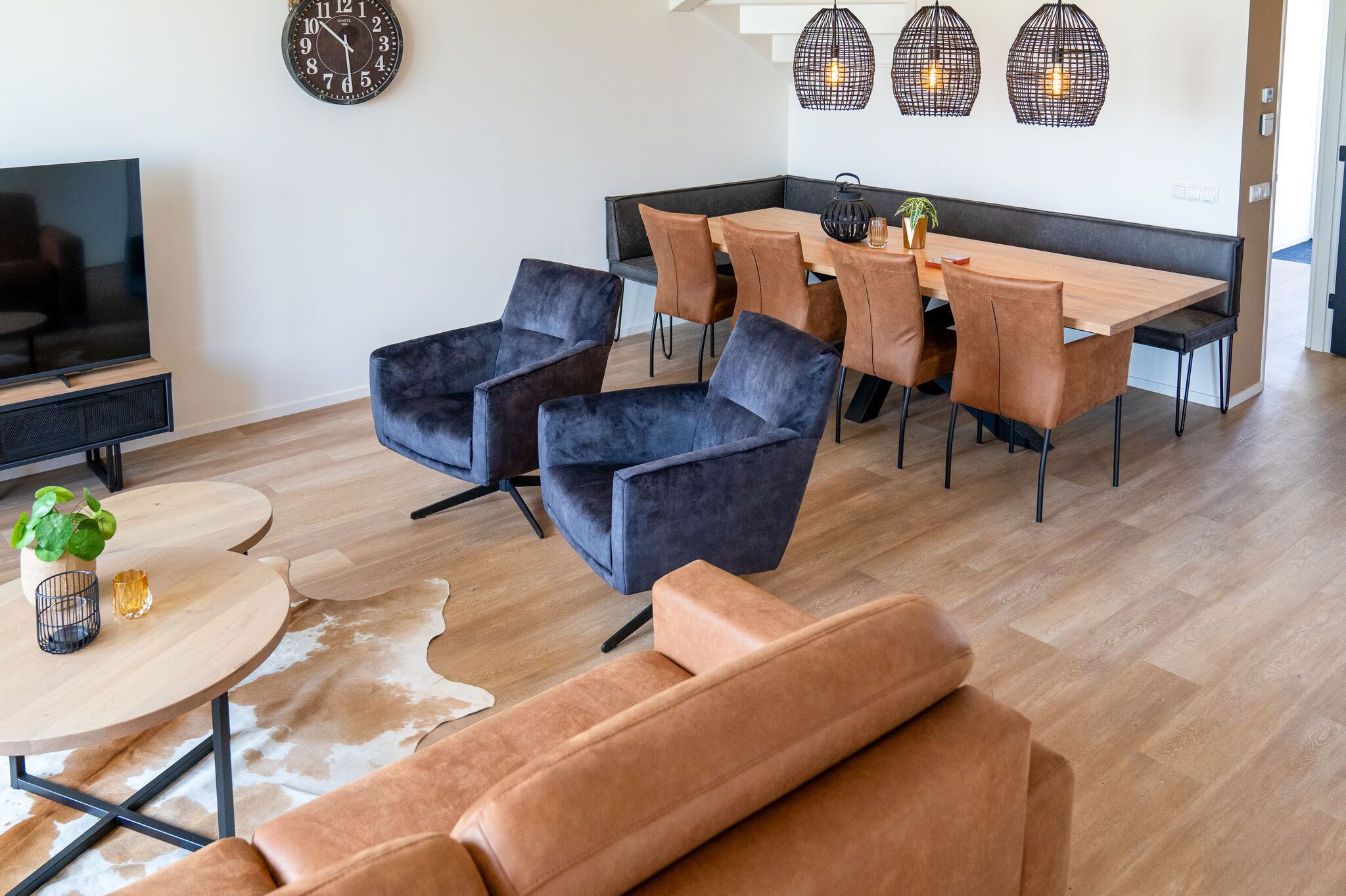 Un salon moderne avec un canapé, une table basse et un téléviseur. Il y a également un coin repas avec une table et des chaises.