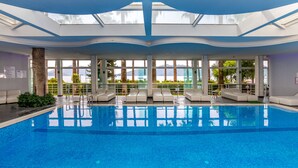 An indoor swimming pool with clear views of the outdoors, including palm trees and mountains. - Prime Beach Hotel - All inclusive (Marmaris)