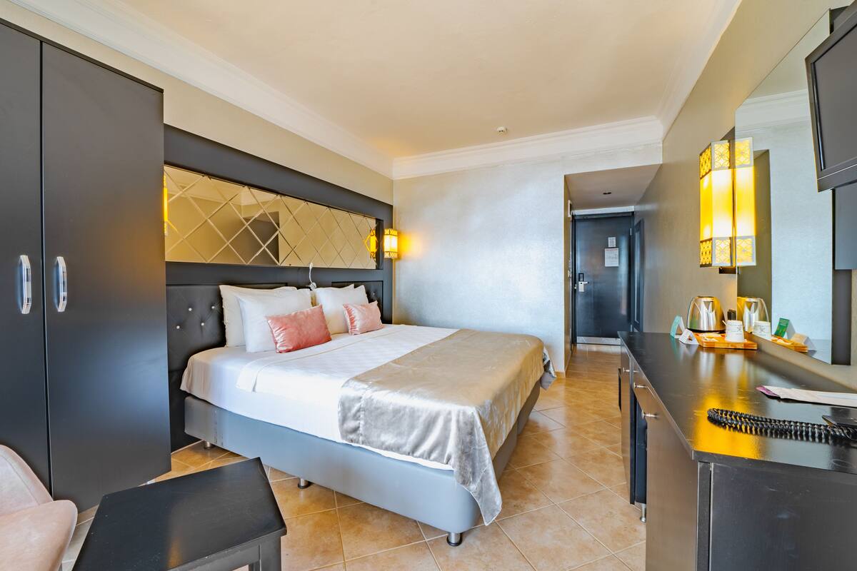 Una habitación de hotel moderna con una cama grande, un escritorio y un armario.