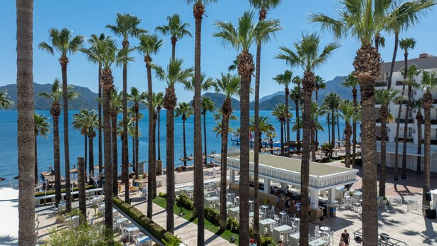A beachfront hotel with palm trees, outdoor seating, and a view of the sea. - Prime Beach Hotel - All inclusive (Marmaris)