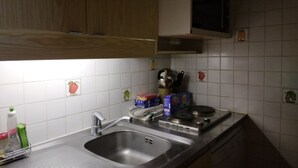 A kitchen with a stainless steel sink, wooden cabinets, and a microwave.