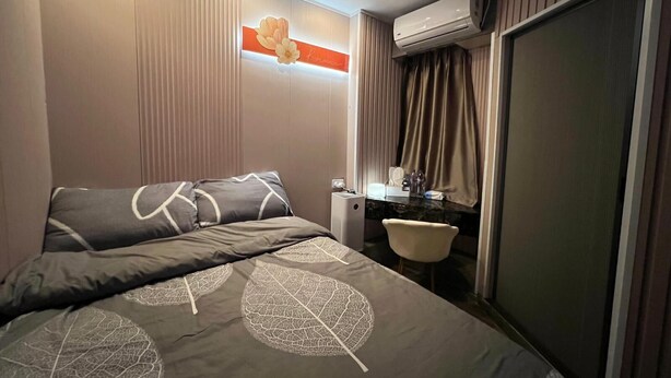 Habitació d'hotel amb llit, una taula de nit, mirall, aire condicionat i una porta corredissa.