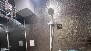 Un bany modern amb una paret negra amb relleu, un vàter blanc, un bidet i un lavabo amb productes de tocador.