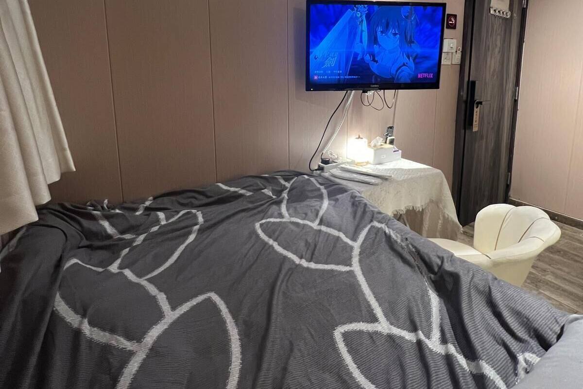 Une chambre d’hôtel avec un lit, une télévision, une petite table avec une lampe et une chaise.
