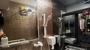 Bany modern amb paret amb relleu, un lavabo, un vàter, una dutxa i un assecagats mans.