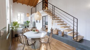 A modern interior with a dining area, staircase, and wooden flooring.