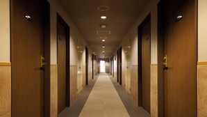 A long, narrow hotel corridor with wooden doors on both sides and a carpeted floor. - Centurion Hotel Hamamatsu (Hamamatsu)