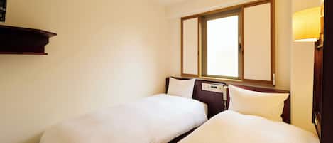Une chambre d’hôtel avec deux lits simples, une fenêtre donnant sur un paysage agréable, une table de chevet et une lampe fixée au mur.