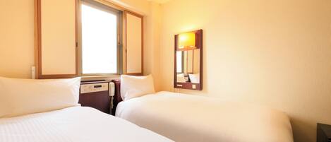A hotel room with two beds, a bedside table, a lamp, and a window.