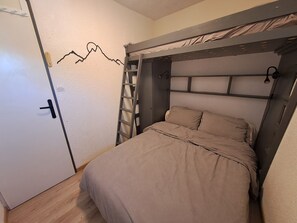Ein Schlafzimmer mit einem Etagenbett, einer Sprosse, einer Tür und einer Wanddekoration.