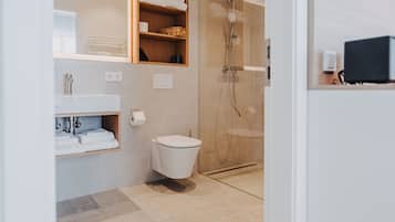 Ein modernes Badezimmer mit Toilette, Dusche und Regalen mit Handtüchern.