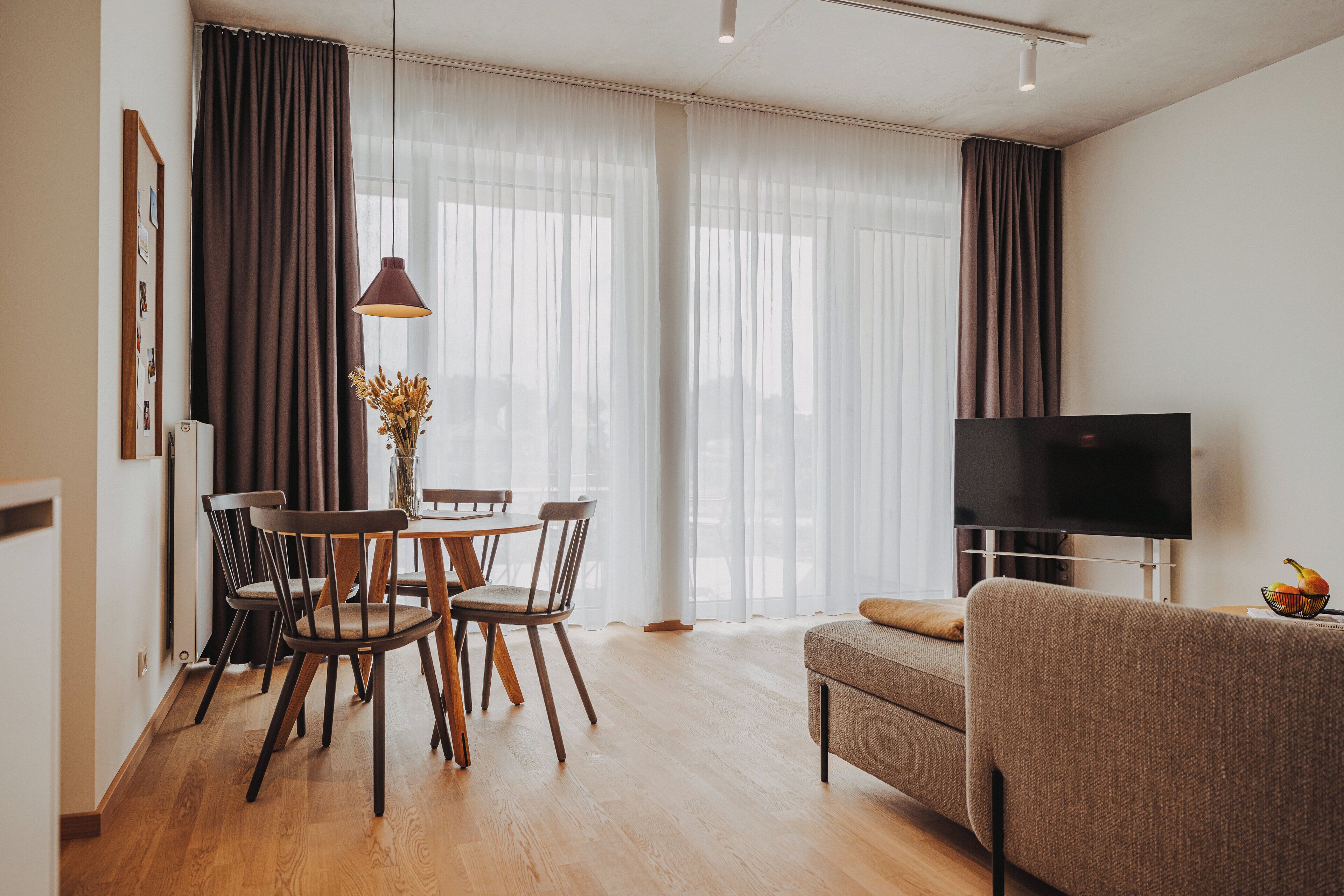 A modern living room with a dining area, a flat-screen TV, and a sofa.