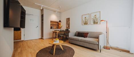 A modern living room with a sofa, coffee table, and a dining area with chairs and a table.