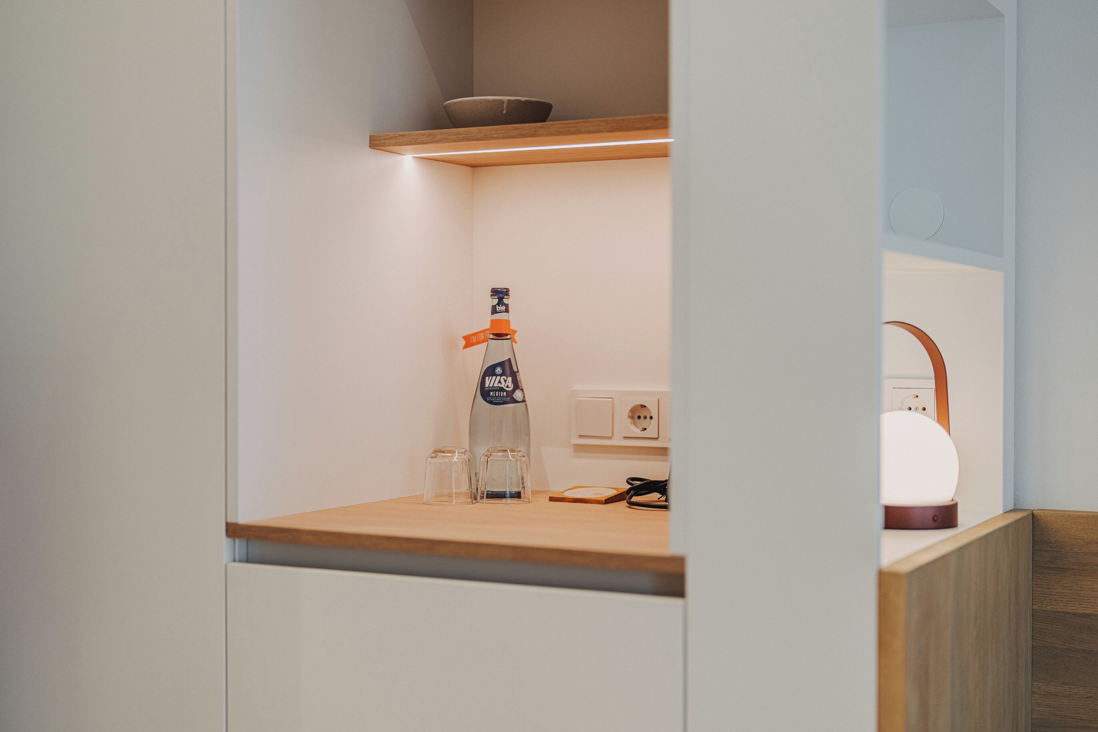 Et moderne køkken med en træbordplade, en Villeroy & Boch flaske, to glas og en kaffemaskine.
