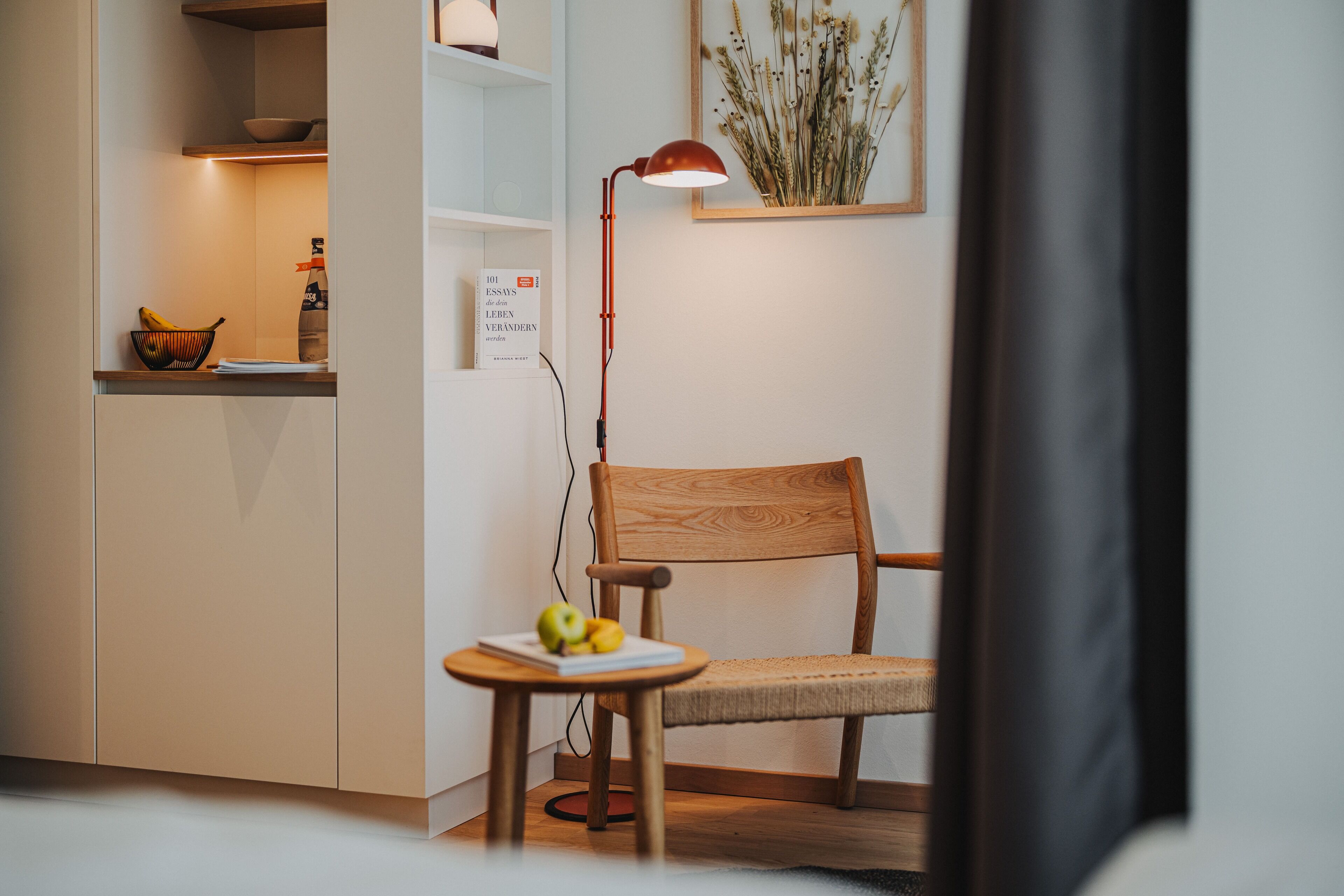 Una cocina moderna con una silla de madera, una mesita con frutas y una lámpara de pie.