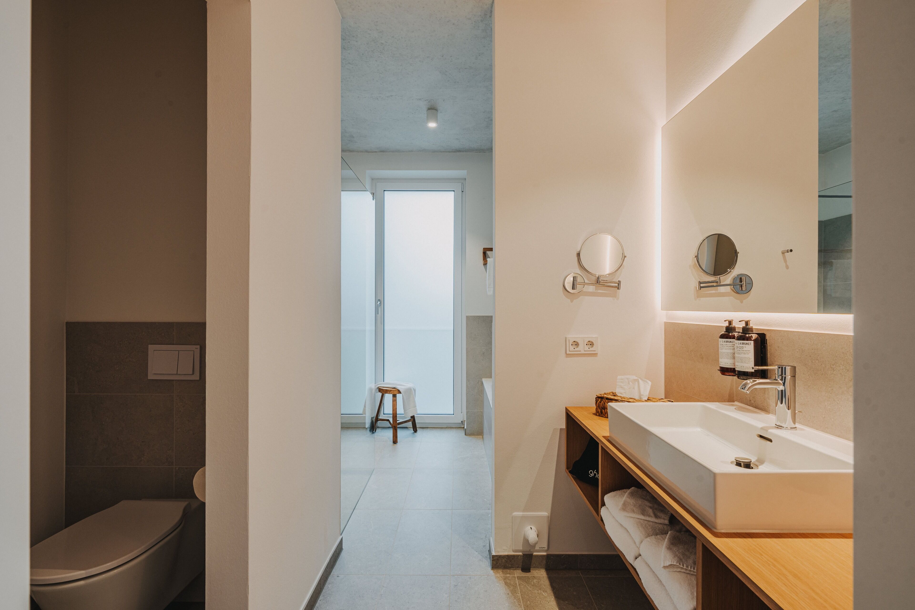 A modern bathroom with a large mirror, a sink, and a toilet.