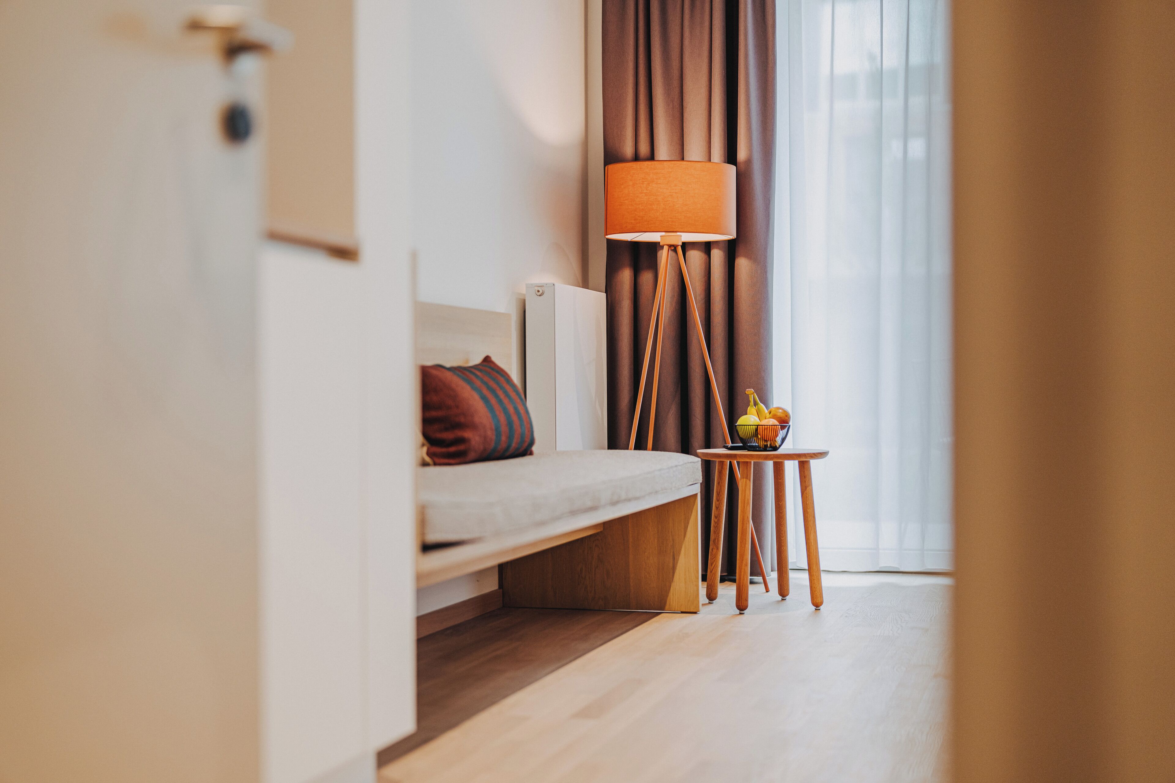 Ein modernes Hotelzimmer mit einer Couch, einem kleinen Tisch mit Obst und einer Stehlampe.