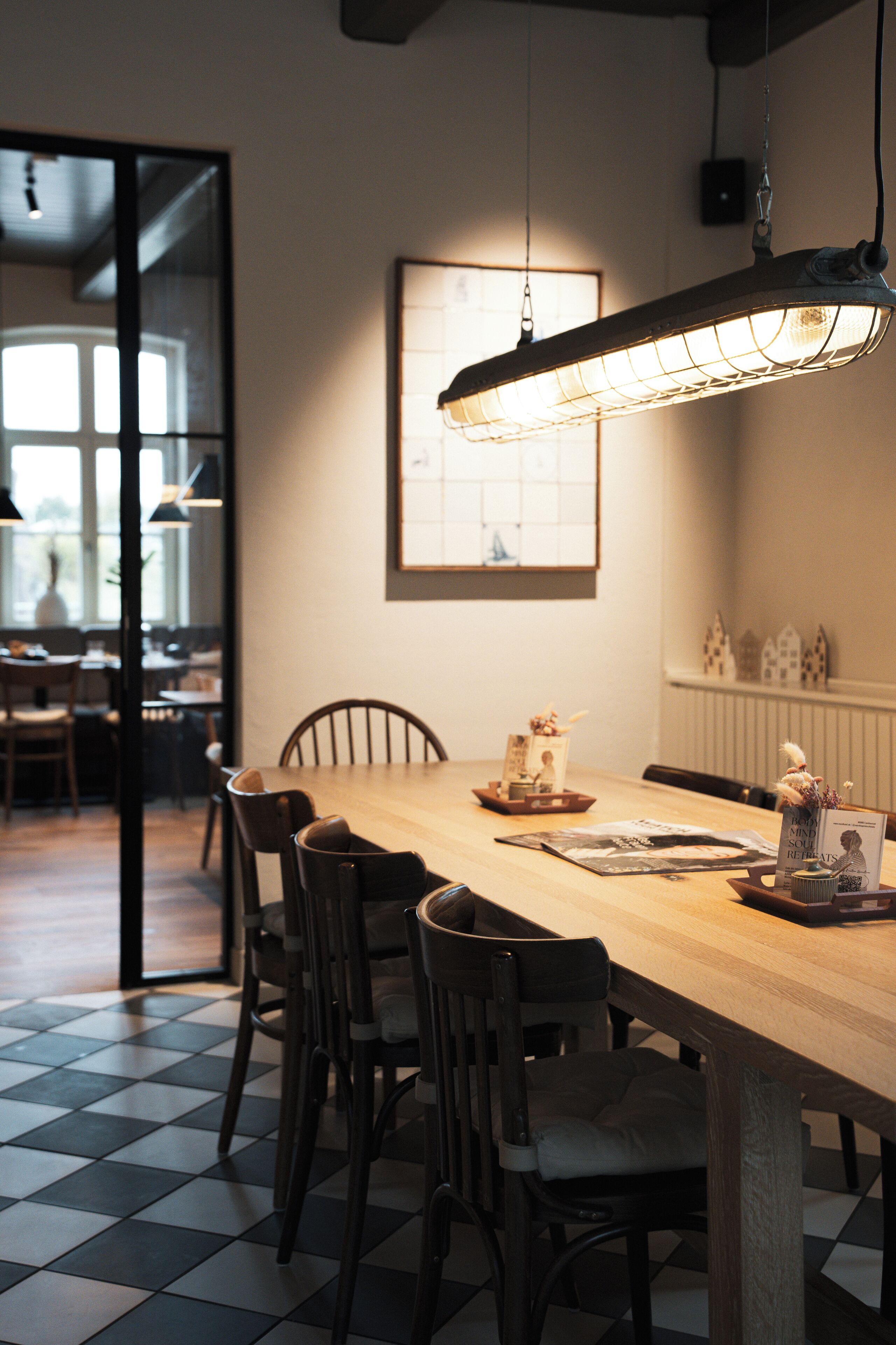 Un comedor con una larga mesa de madera, seis sillas y una lámpara colgante.