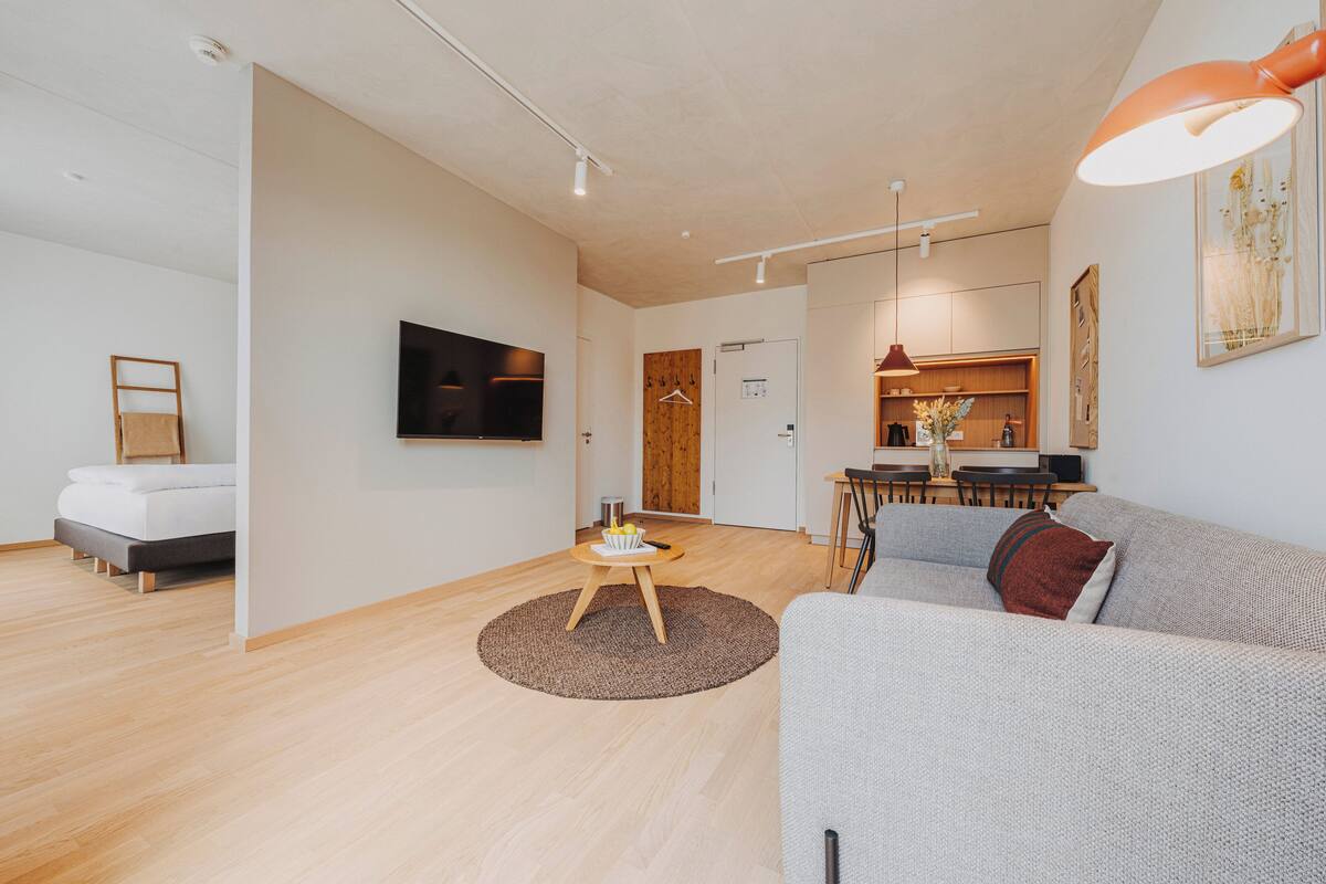 A modern living room with a sofa, a coffee table, and a TV mounted on the wall.