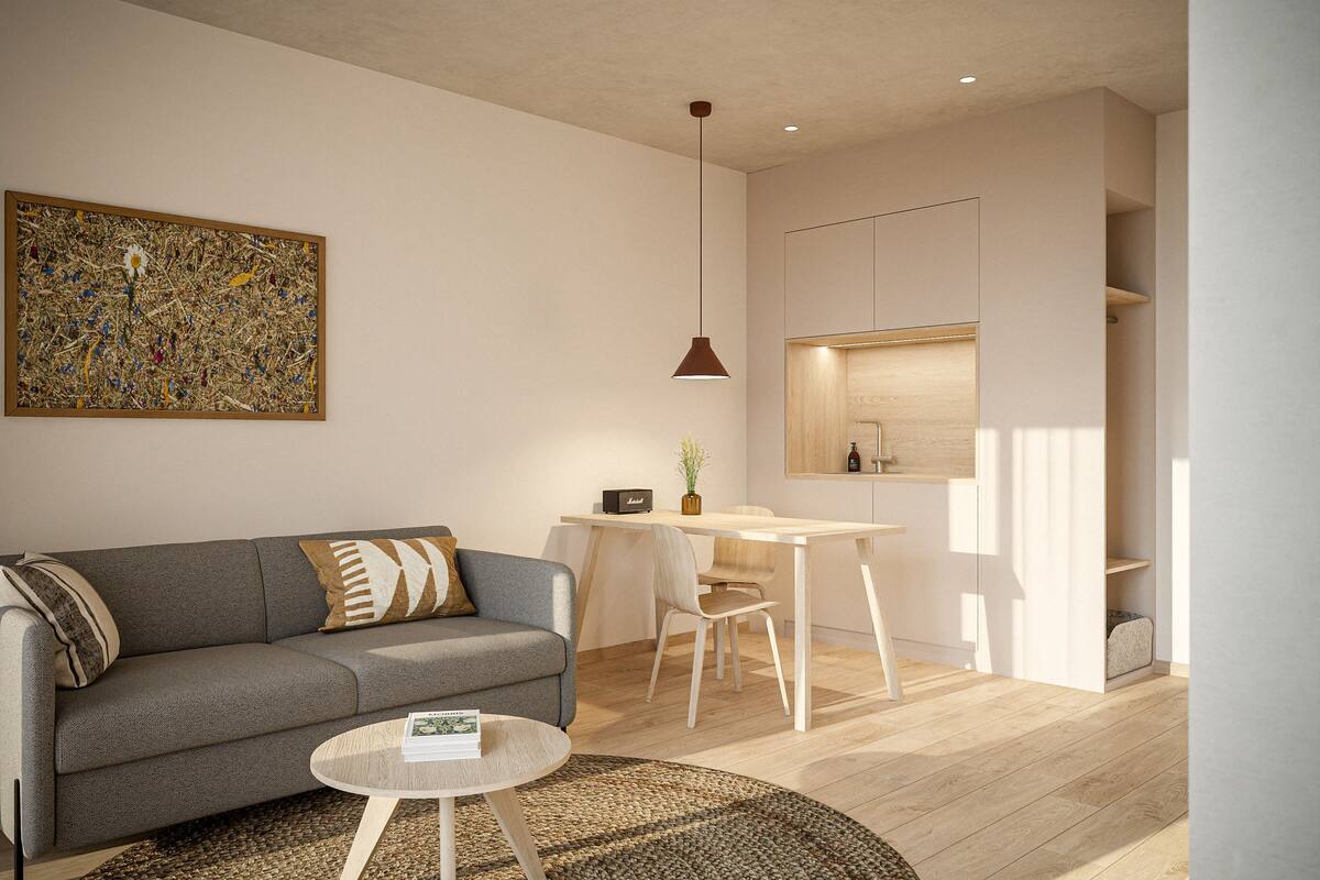 A modern living room with a grey sofa, a small round coffee table, and a painting on the wall.