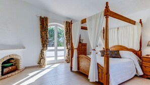 Ein Himmelbett mit weißer Bettwäsche, einem Holzkopfende und Vorhängen.
