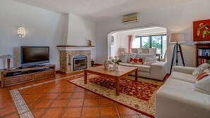 Ein Wohnzimmer mit Kamin, Fernseher, Sofa und Couchtisch.