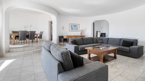 A modern living room with a gray sectional sofa, a wooden coffee table, and a dining area with a wooden table and chairs. - Villa Paraiso Beautiful villa in an enviable position (Carvoeiro)
