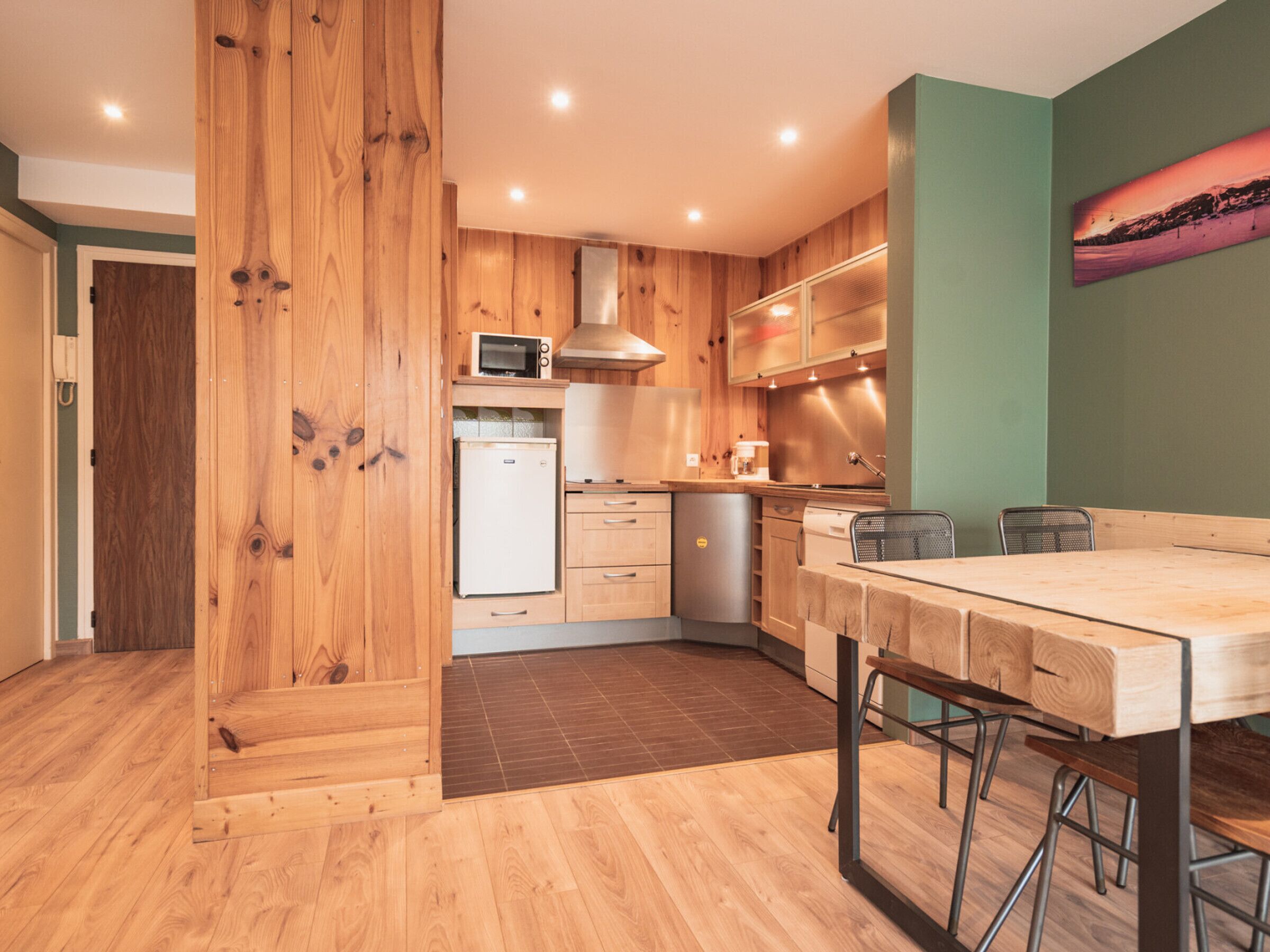 Une cuisine moderne dotée de meubles en bois, d’un four à micro-ondes, d’un réfrigérateur et d’un coin repas avec une table et des chaises.