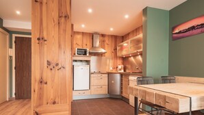 A modern kitchen with wooden cabinets, a microwave, a refrigerator, and a dining area with a table and chairs.