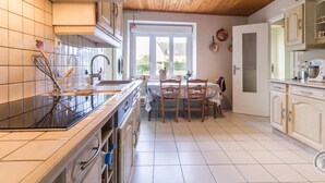 A kitchen with wooden ceiling, white tiles, a dining table with chairs, and cabinets. - Charming house in Normandy, pets allowed, parking (Hautteville-Bocage)