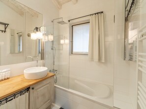 Ein modernes Badezimmer mit einem weißen Waschbecken, einer Duschkabine und einem Fenster mit Vorhängen.