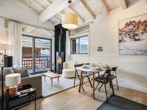 Una sala de estar moderna con chimenea, un comedor y un amplio ventanal con vistas a una terraza.